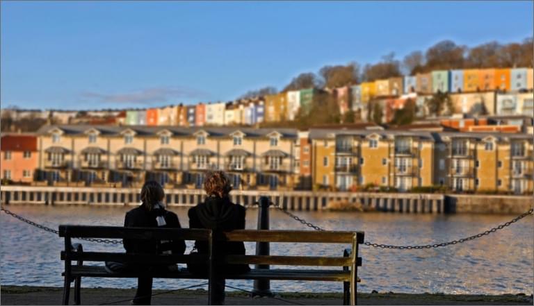 A couple sitting in front of a row of houses in the city of Bristol